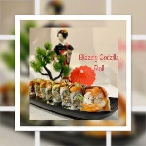A sushi roll garnished with sauce and toppings is presented on a black plate. A small parasol and a figurine of a woman in traditional attire are in the background. Text reads "Blazing Godzilla Roll.