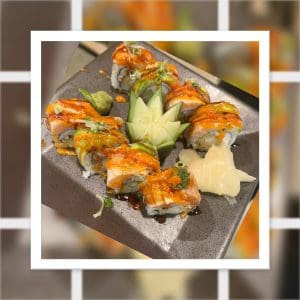A plate of sushi rolls topped with sauce, garnished with wasabi, pickled ginger, and an intricately carved cucumber slice on the side.