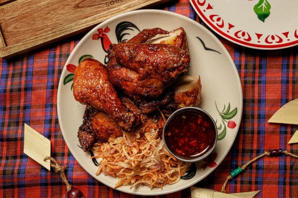 Juicy fried chicken with coleslaw and dipping sauce on a decorative plate.